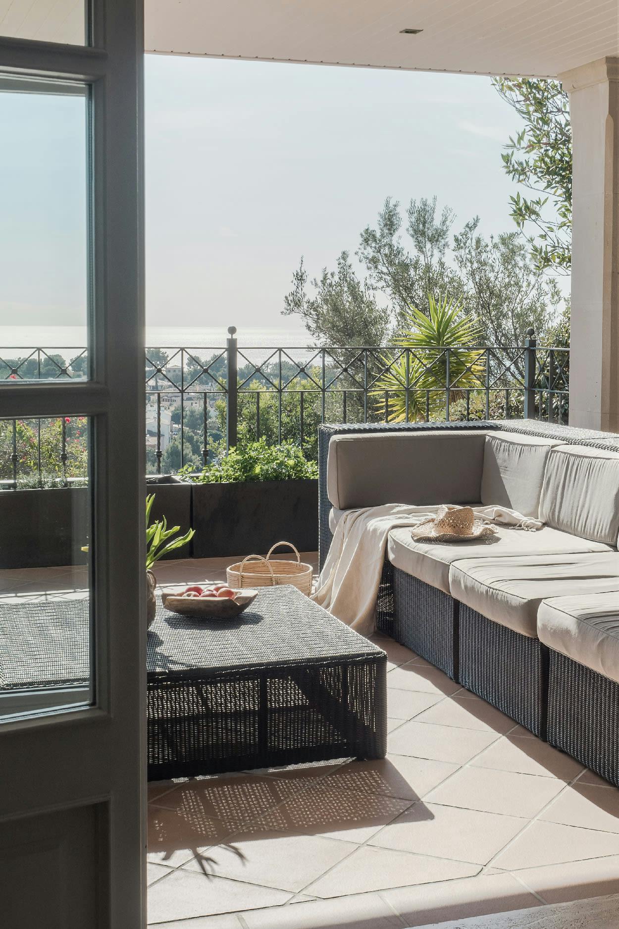 The image showcases a spacious outdoor patio area with a large glass door that opens to a beautiful view of the ocean. The patio is furnished with a couch, a chair, and a table, creating a comfortable and inviting space for relaxation and socializing.

A bowl is placed on the table, adding a touch of elegance to the scene. The patio is surrounded by a brick walkway, which adds to the overall aesthetic of the outdoor area. The presence of a potted plant near the couch further enhances the ambiance of the space.