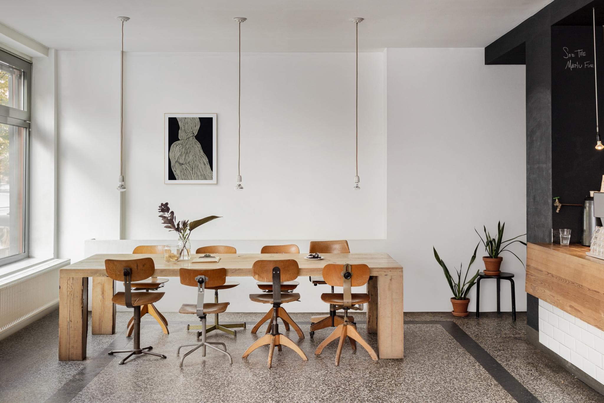 The image features a modern, white-themed dining room with a wooden table and chairs, a potted plant, and a vase.