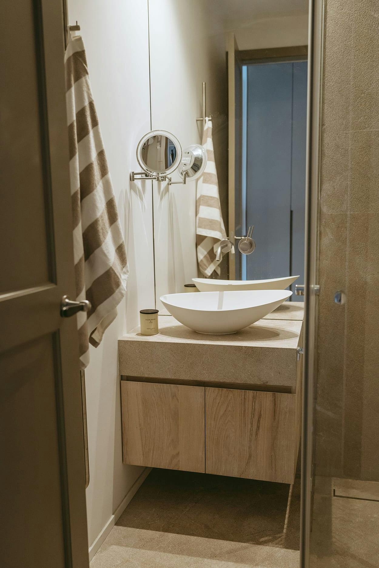 The image features a bathroom with a white sink, a mirror, a towel rack, and a shower.