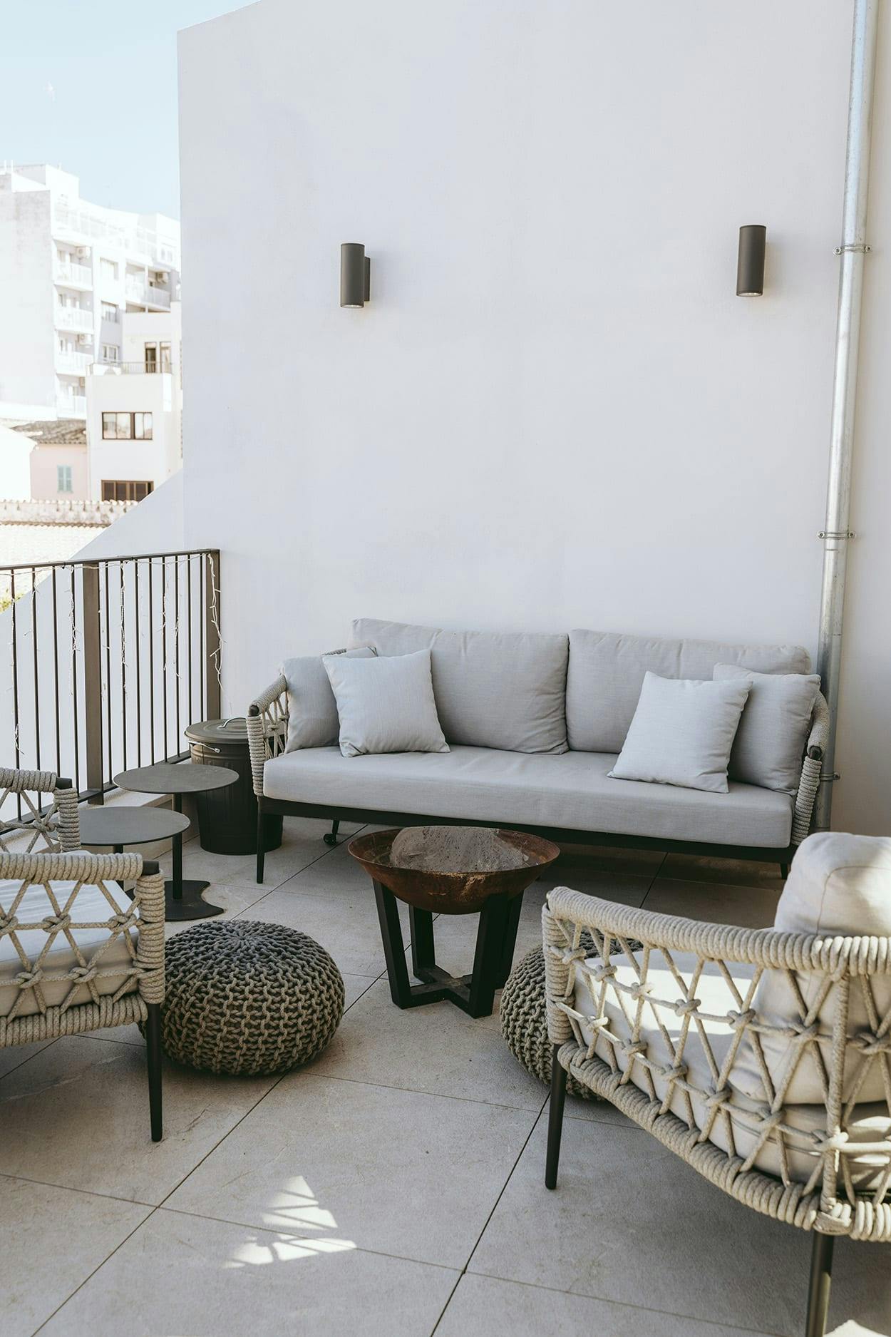 The image features a white patio with a couch, a chair, and a table.
