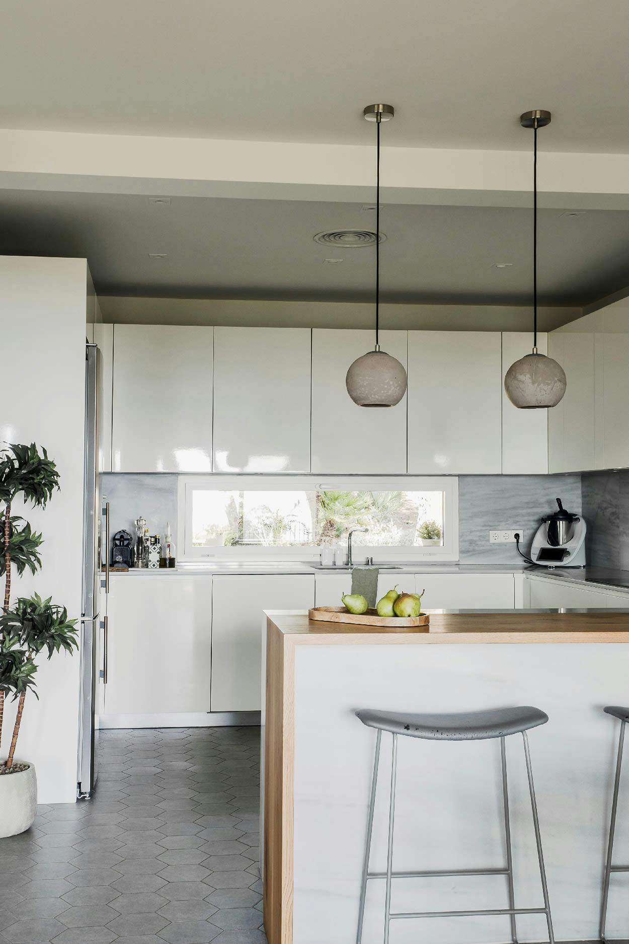 The image features a modern kitchen with white cabinets, a white countertop, and a stool.