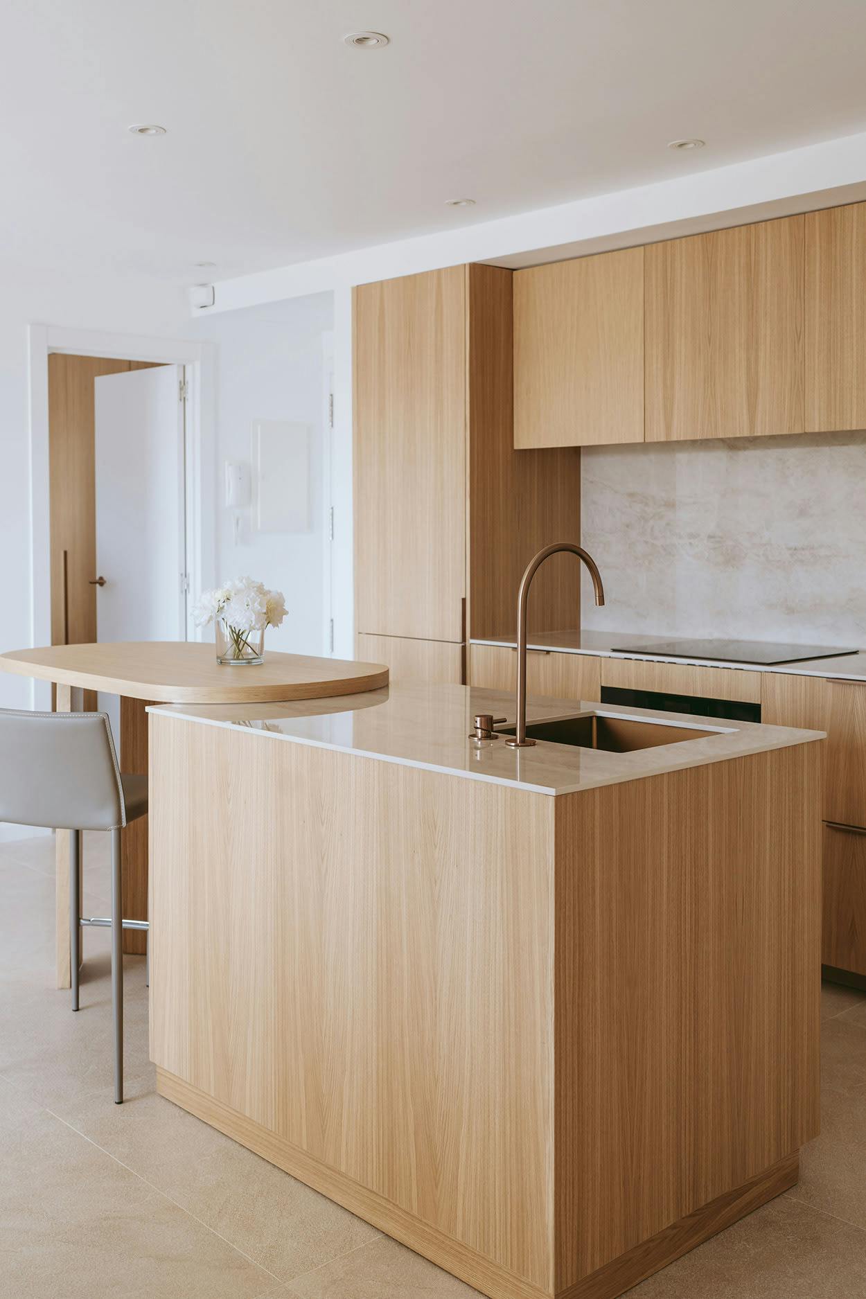 The image features a modern kitchen with wooden cabinets, a large island, and a sink.
