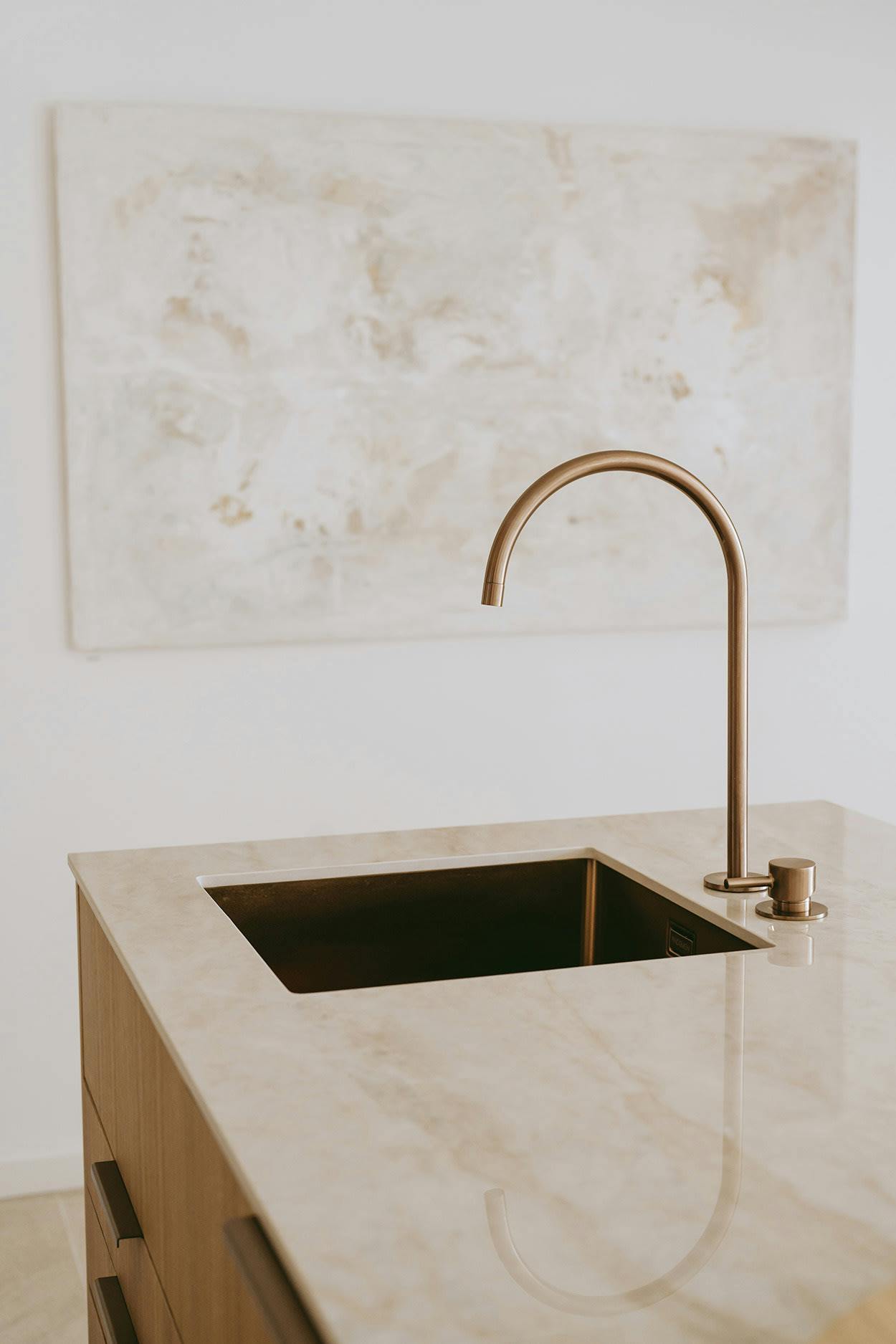 The image features a large, marble-like sink with a gold faucet, placed on a white countertop.