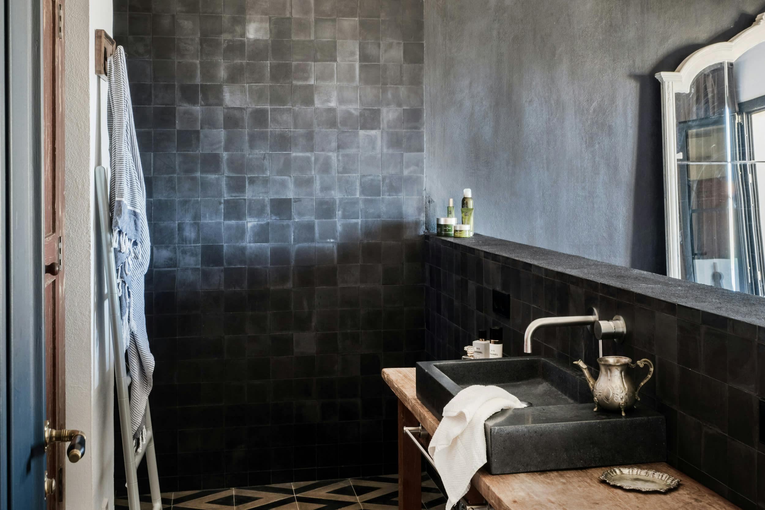 The image features a black and gray bathroom with a sink, a mirror, and a window.
