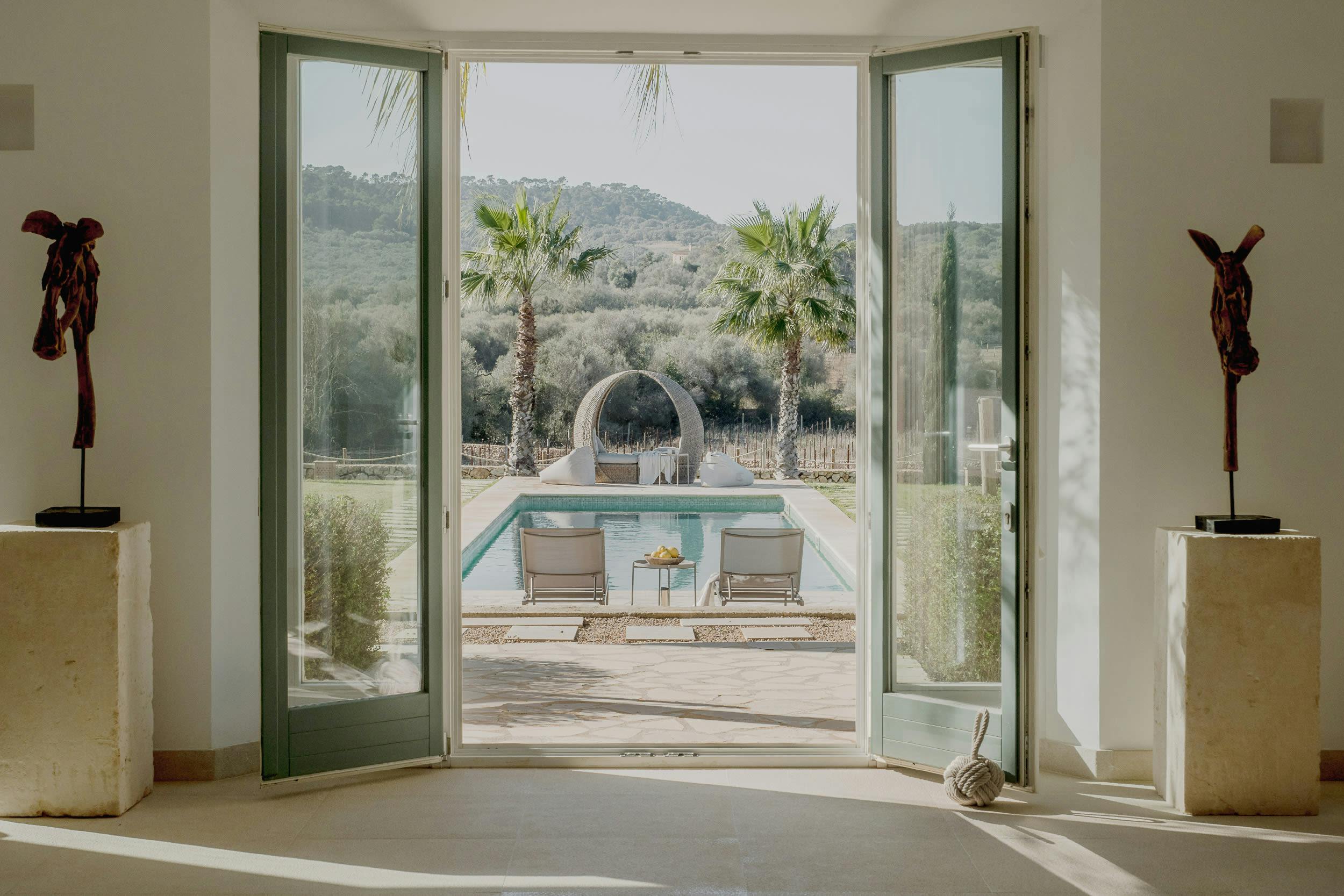 The image features a large glass door leading to a pool area, with a pool in the background.