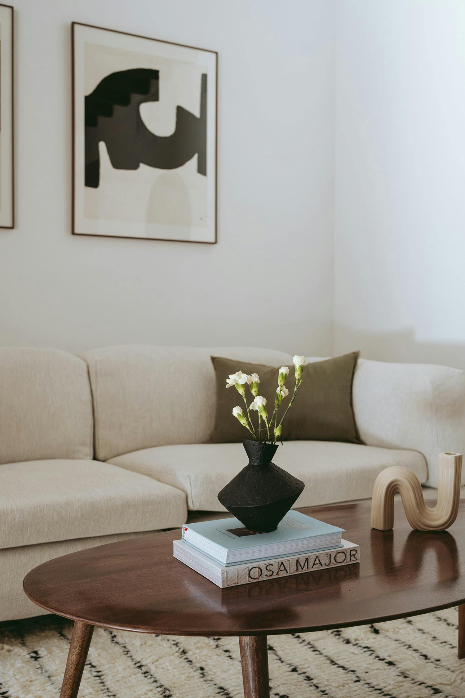 The image features a white living room with a couch, a coffee table, and a vase of flowers.