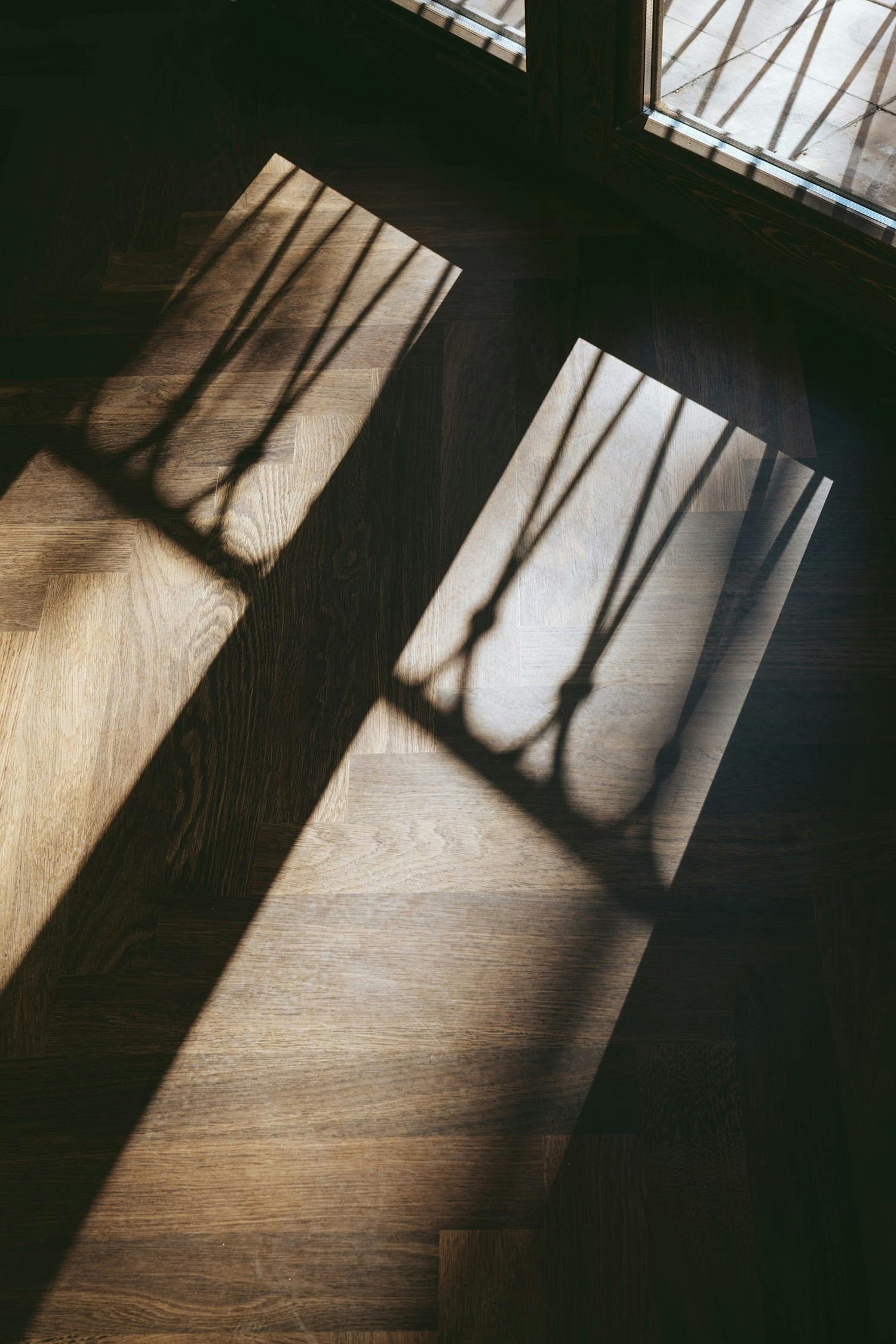 A wooden floor with a shadow cast by a window is shown in the image.