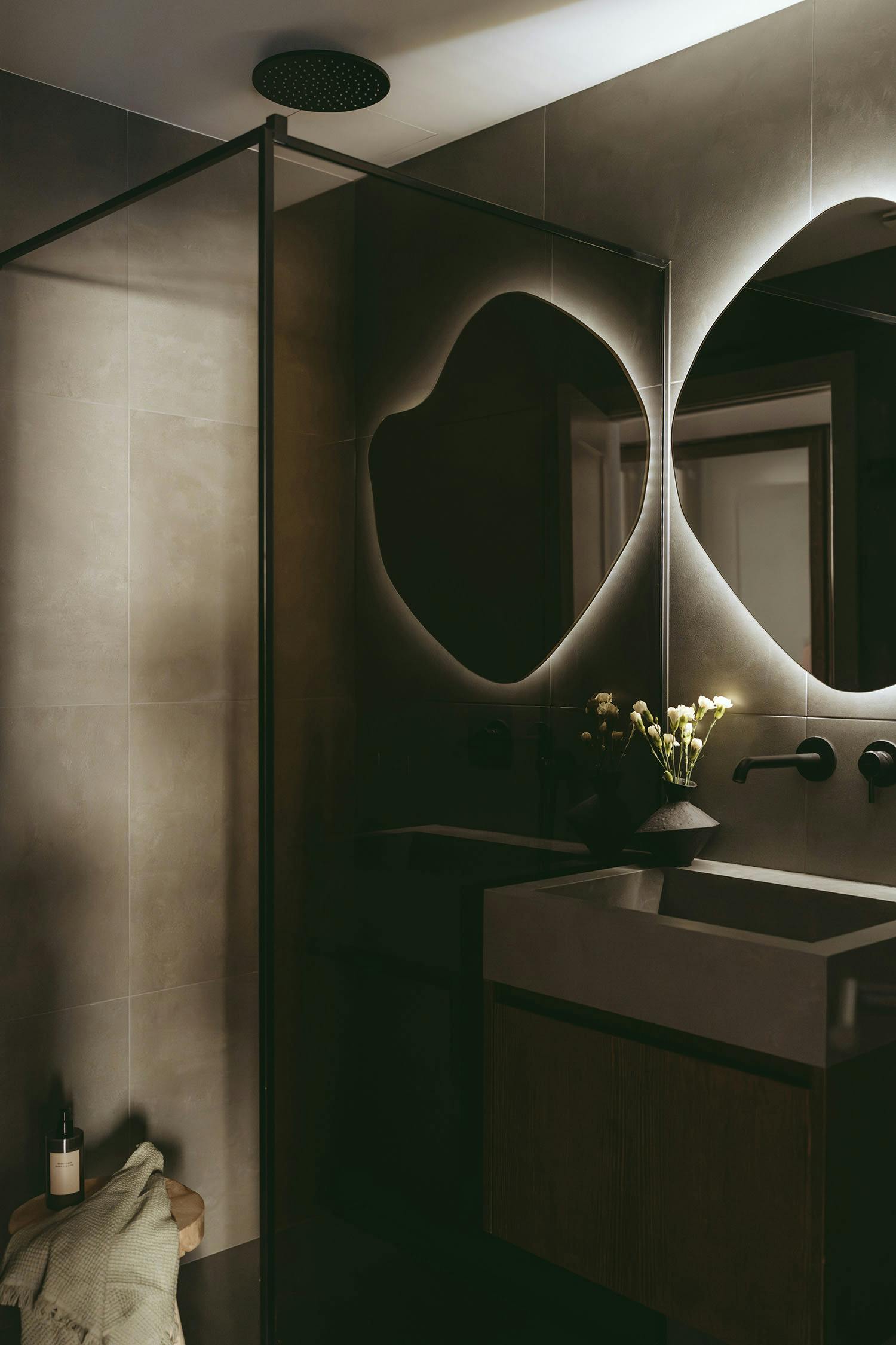 The image features a bathroom with a large mirror, sink, and a vase of flowers.