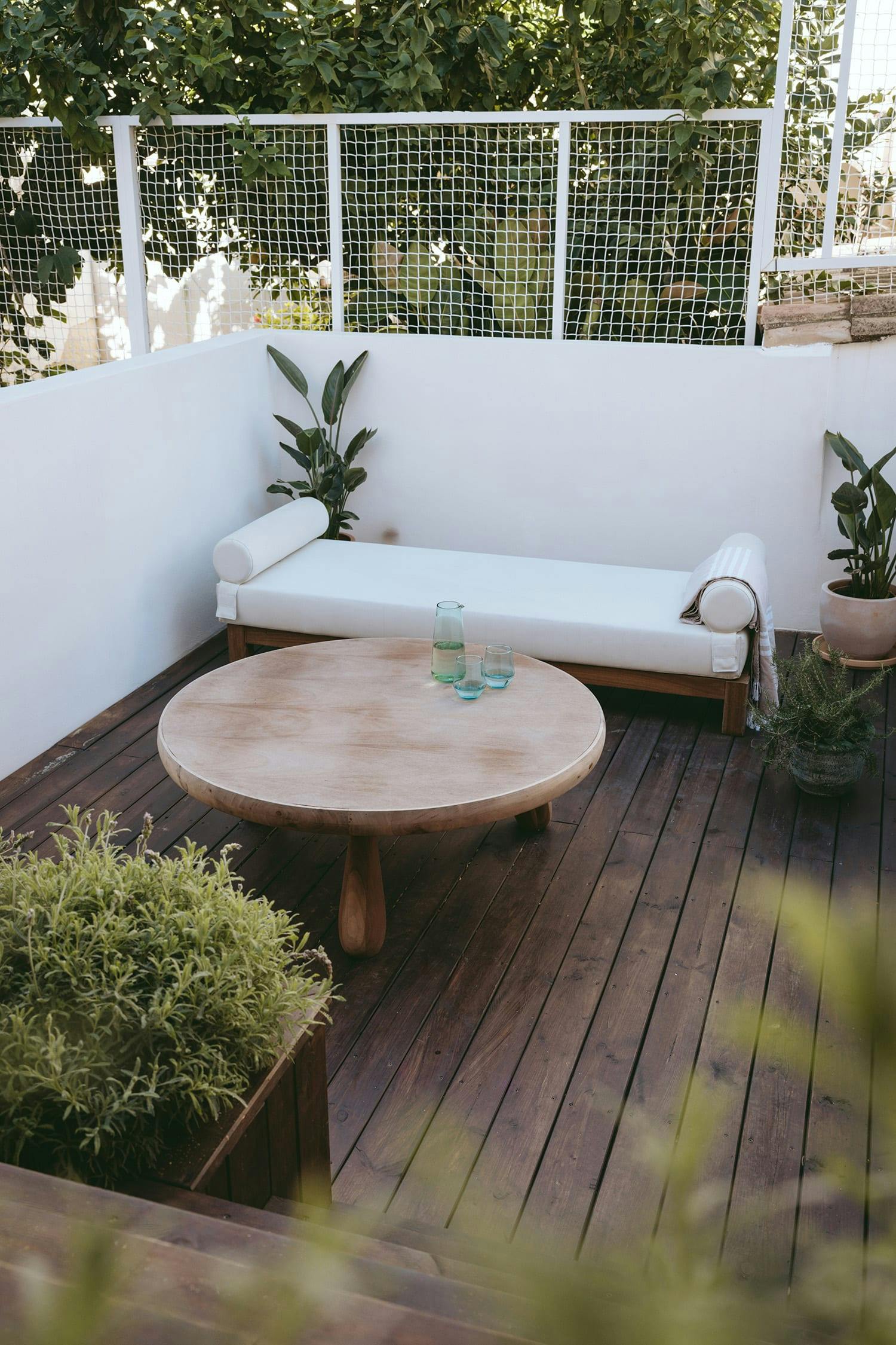 The image features a wooden deck with a white couch and a table, both placed on a wooden deck.