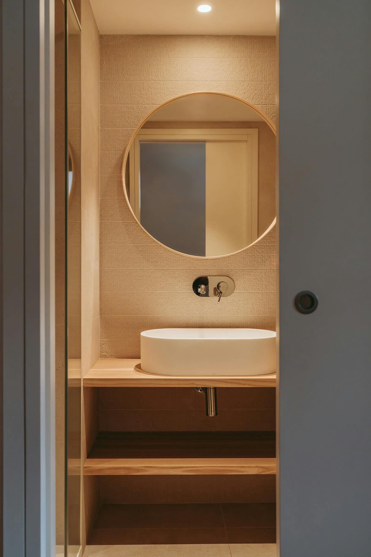 The image features a small bathroom with a white sink, a mirror, and a wooden cabinet.