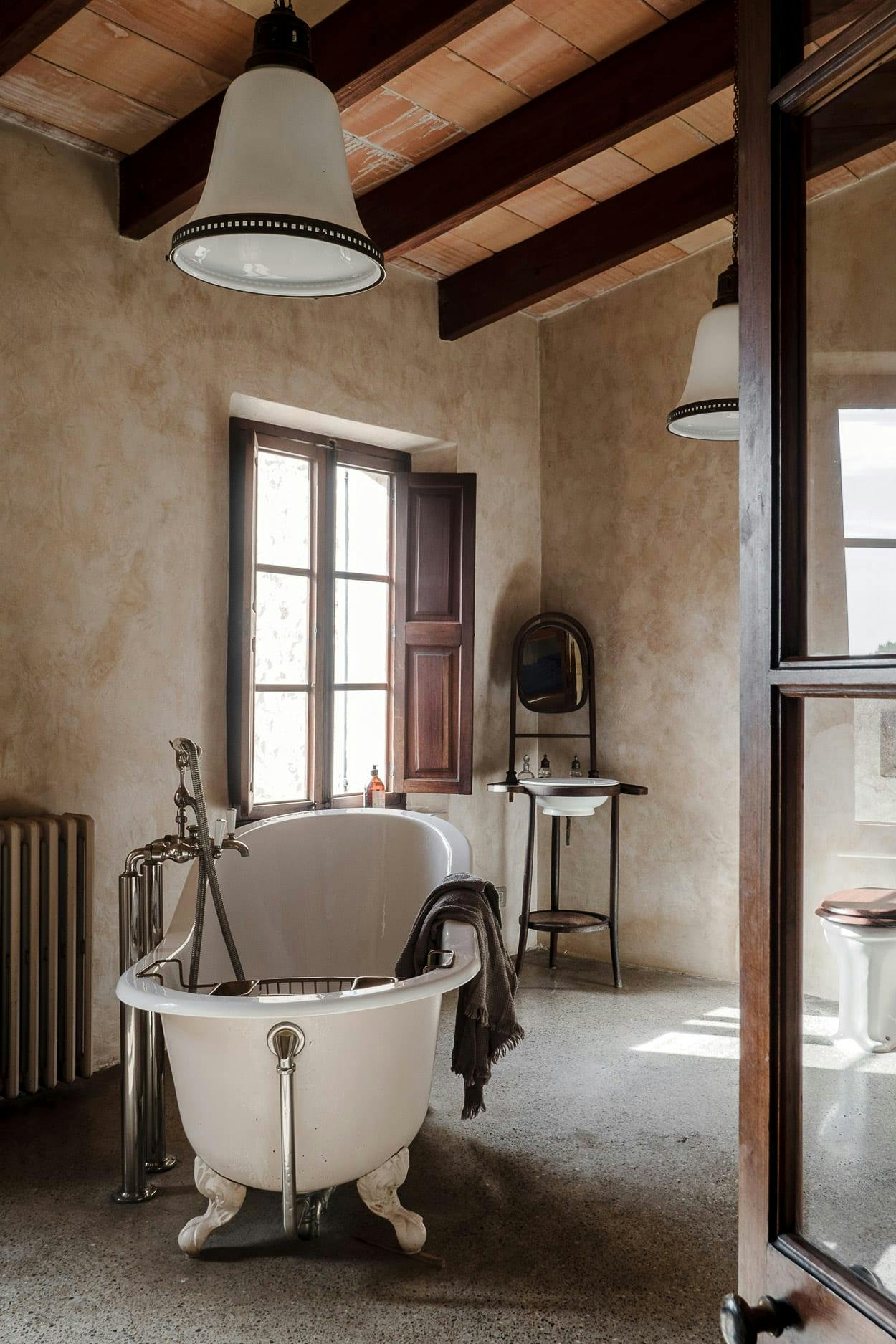 The image features a large, white claw-foot bathtub in a bathroom with a window, a sink, and a chair.