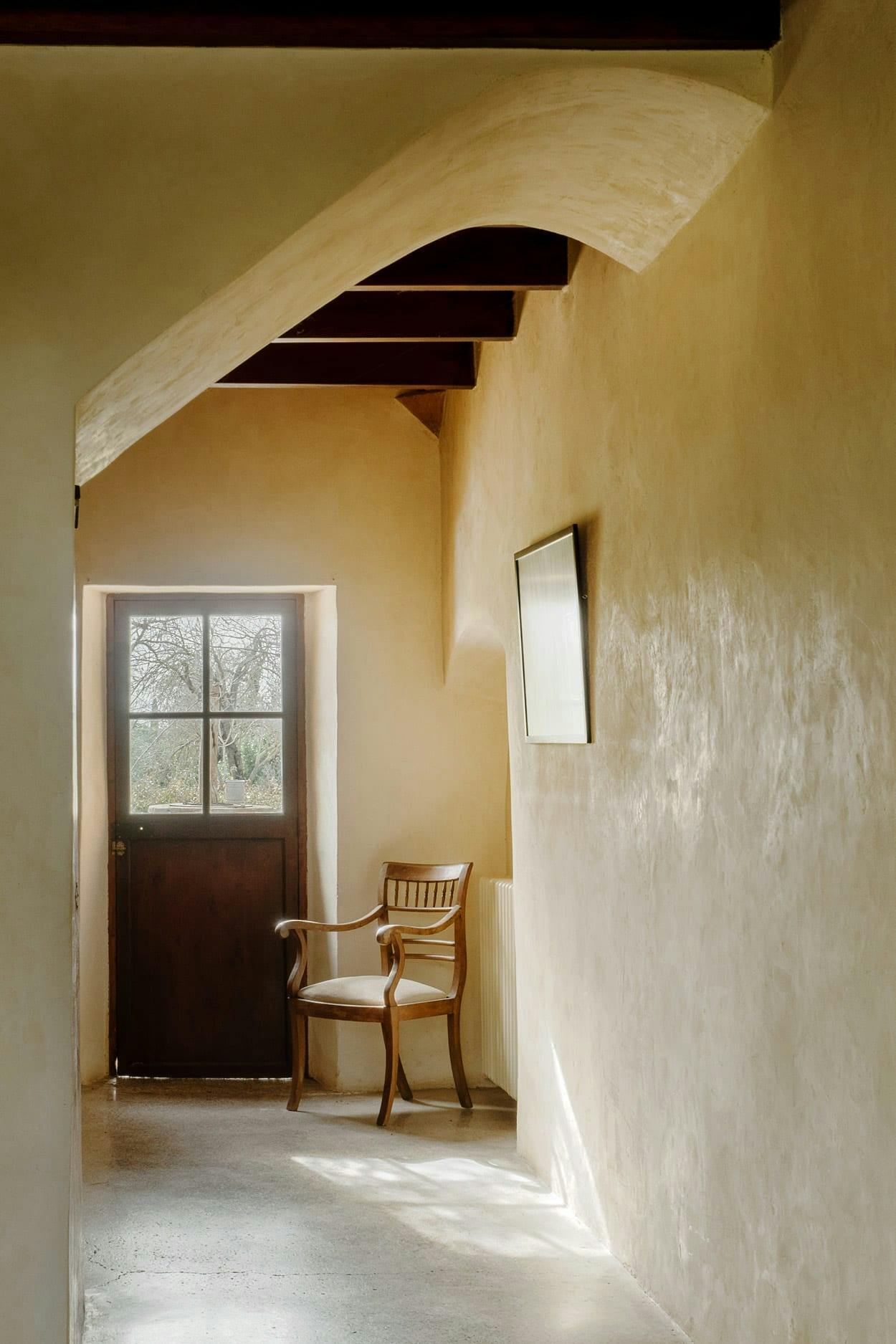 A chair is sitting in a room with a window, and the room is painted in a light yellow color.