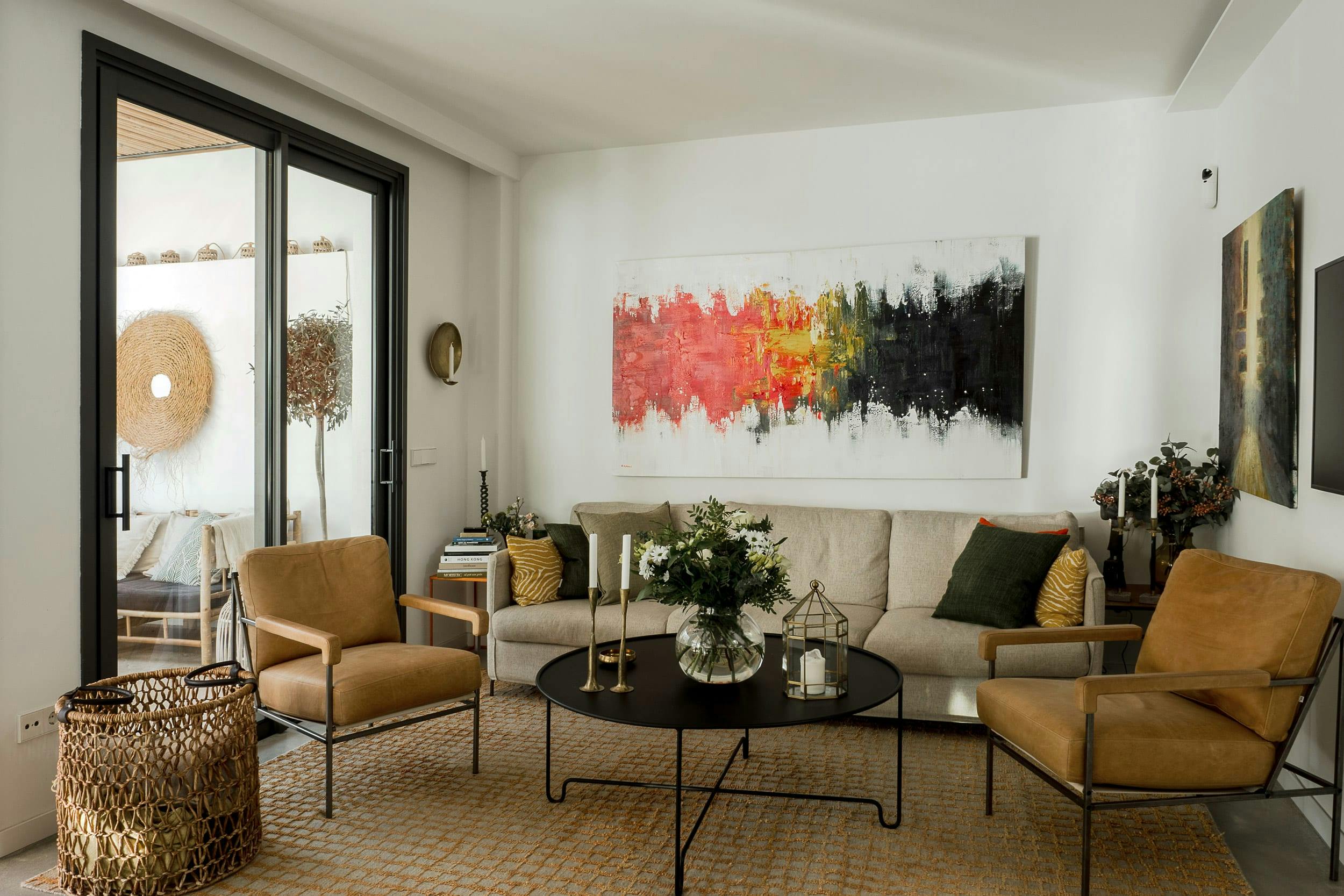 The image features a modern, well-lit living room with a large couch, two chairs, a coffee table, and a painting on the wall.