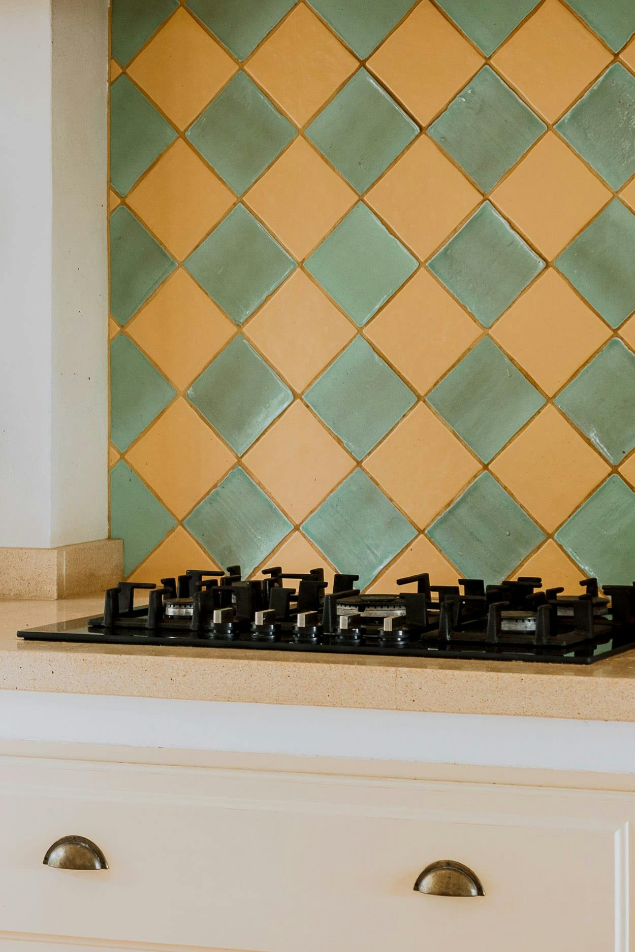 The image features a kitchen with a white stove top oven and a blue and yellow checkered tile backsplash.