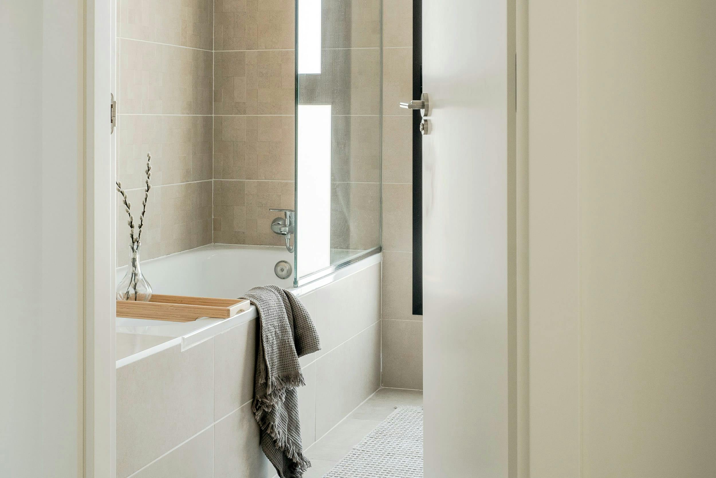 The image features a bathroom with a white bathtub, a window, a sink, and a mirror.