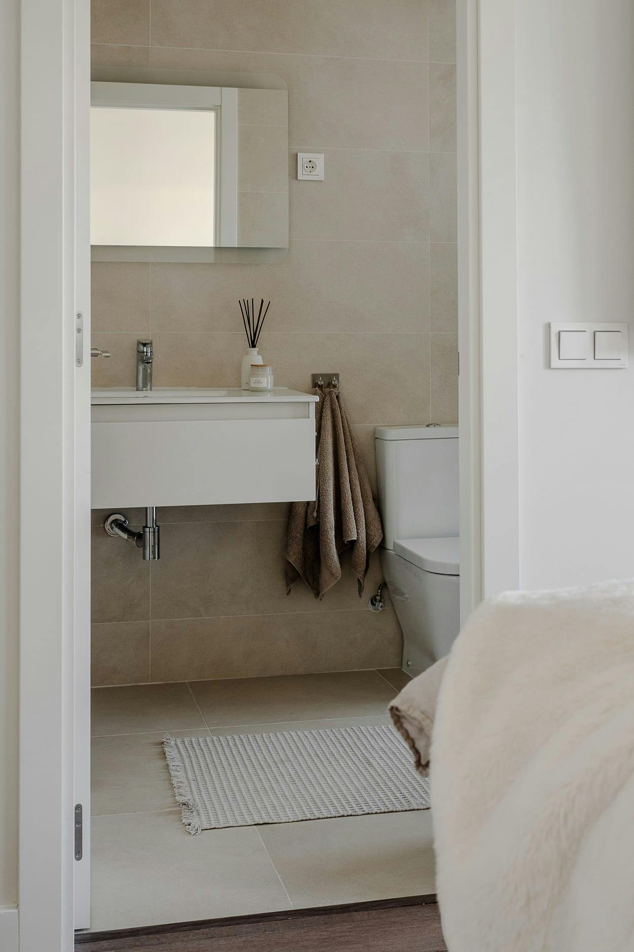 The image features a clean, white bathroom with a toilet, sink, and mirror.