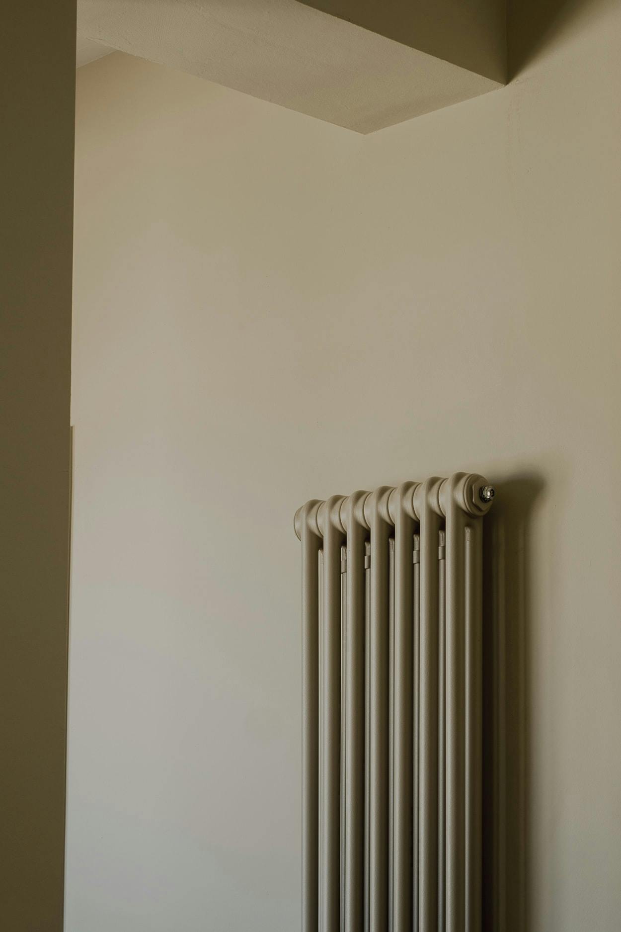 A large, white, and silver radiator is mounted on the wall in a room, providing heat to the space.