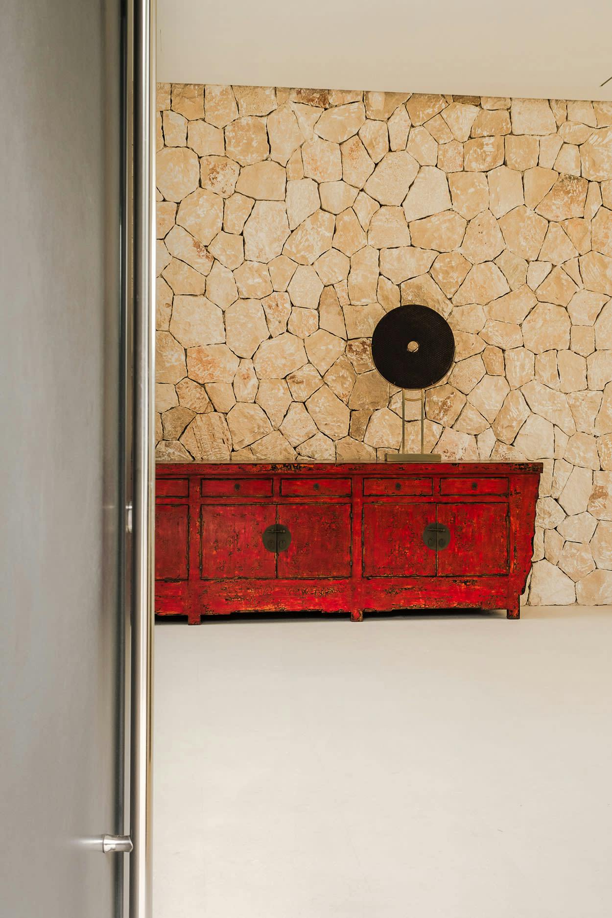 The image features a wooden dresser with a black and red color scheme, placed next to a wall with a stone wallpaper design.